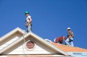 three roofers standing on top of residential home roof
