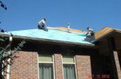 two men working on top of home roof